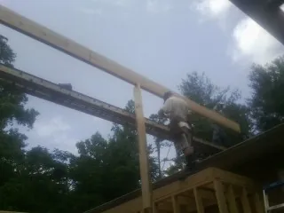 Carpenter setting a ridge beam over a new addition frame — Ice Dam Removal by Roofing Brothers in Harvest