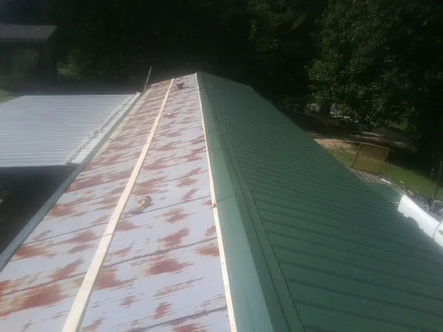 Old rusted panels beside newly installed green metal roofing — Wind Damage Roof Repair by Roofing Brothers in Harvest