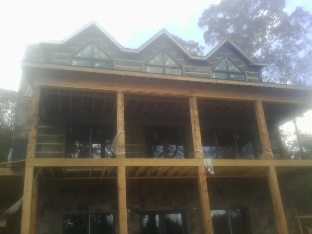 Dormers and porch framing on a large log home under construction — Roof Coating work by our crew in Harvest