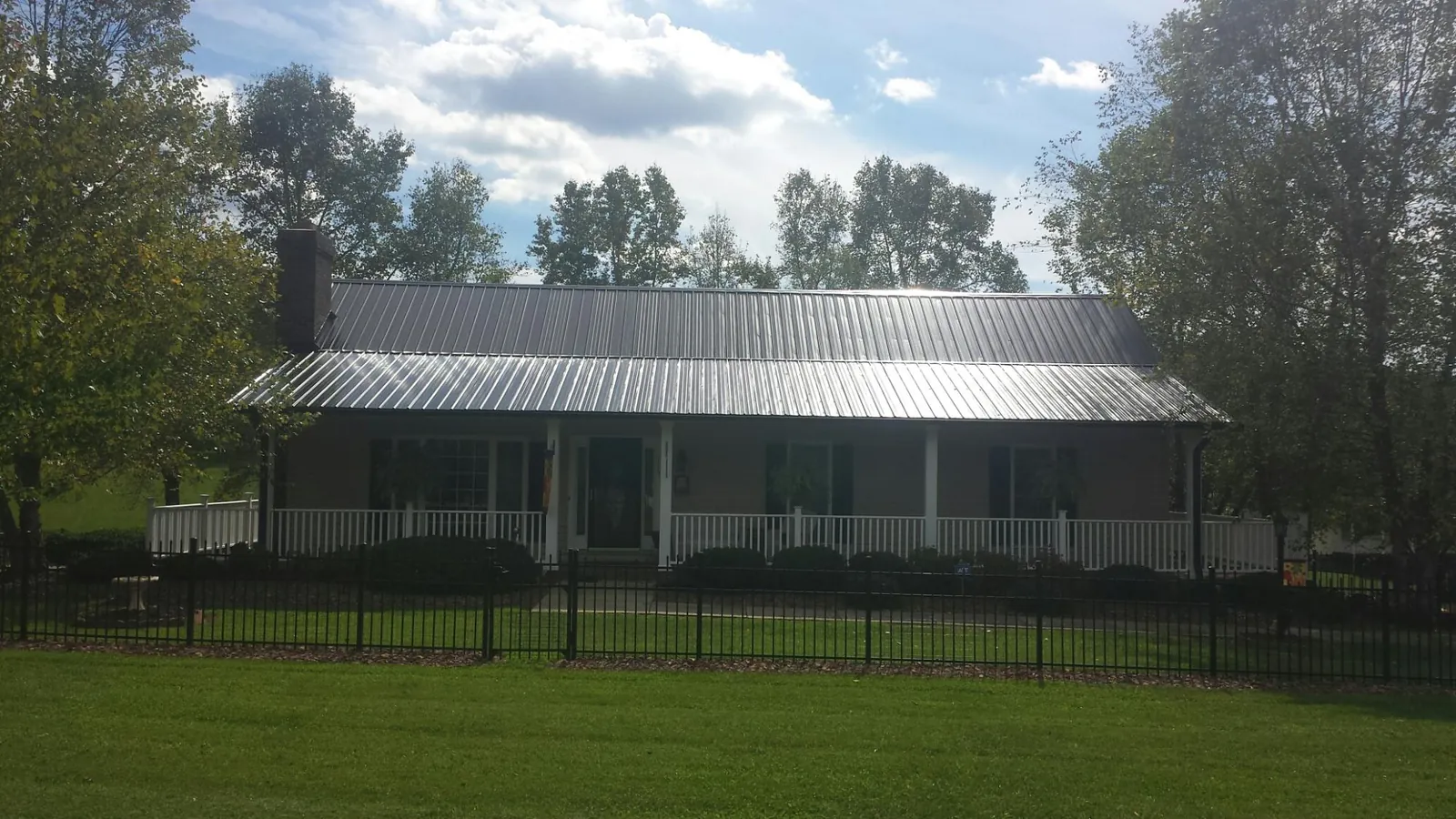 Gray metal roof on a brick ranch with a full width front porch — Gutter Guard Installation work by our crew in Harvest