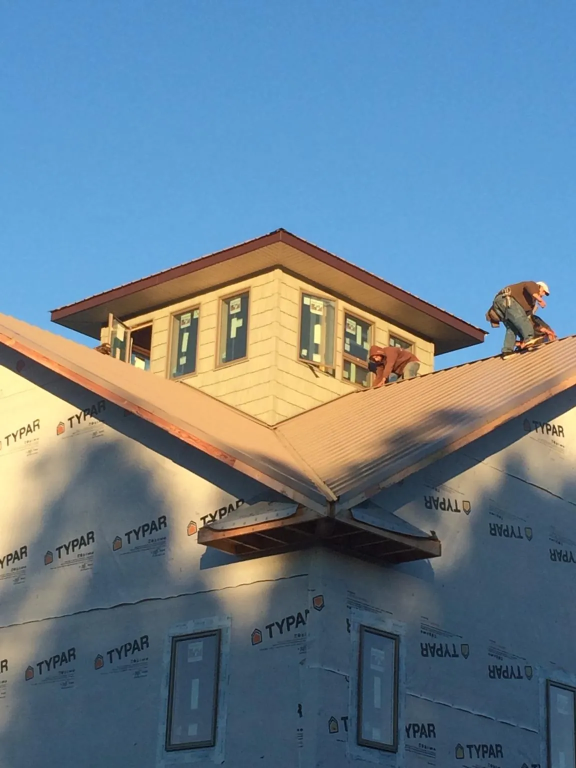 Roofers working around a rooftop cupola on a new metal roof at sunset — Roof Waterproofing in Harvest by Roofing Brothers